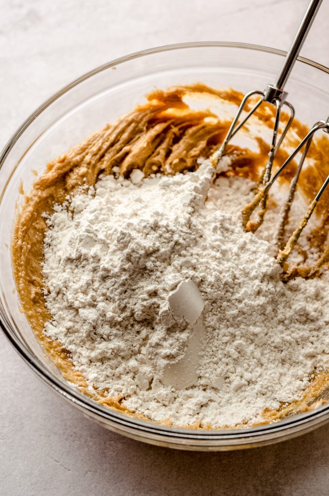 A bowl of ingredients to make peanut butter shortbread with electric beaters in the bowl.