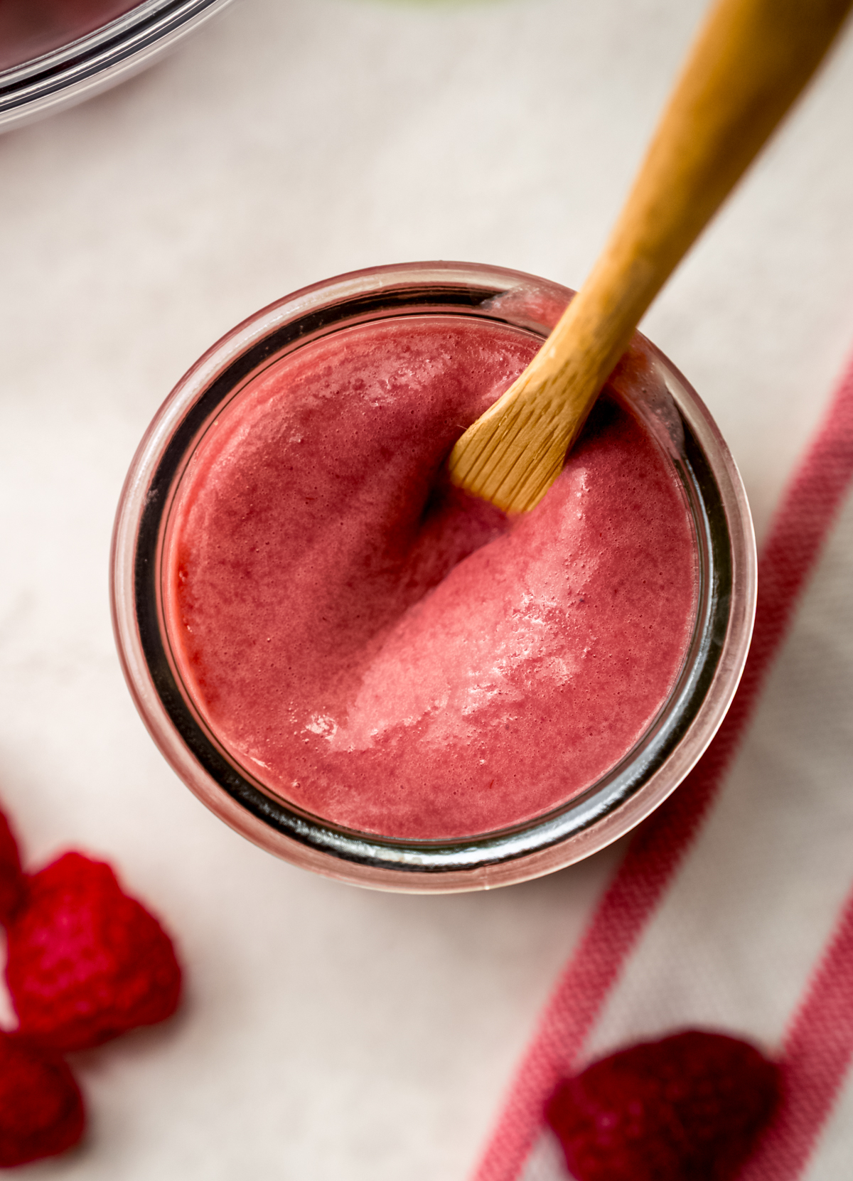 A spoon in a jar of raspberry curd.