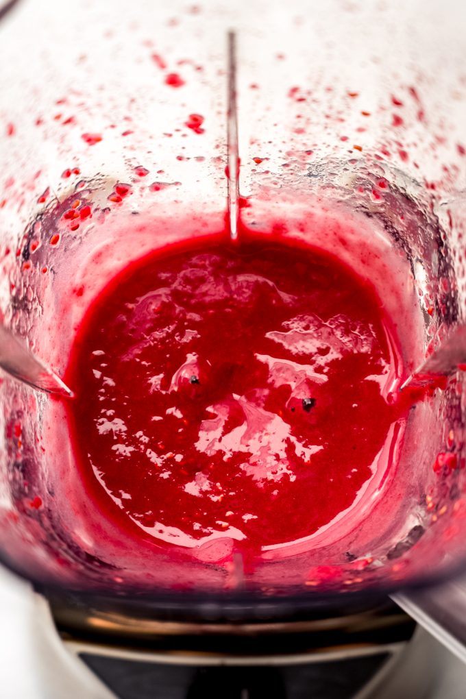 Aerial photo of a blender full of processed raspberries.