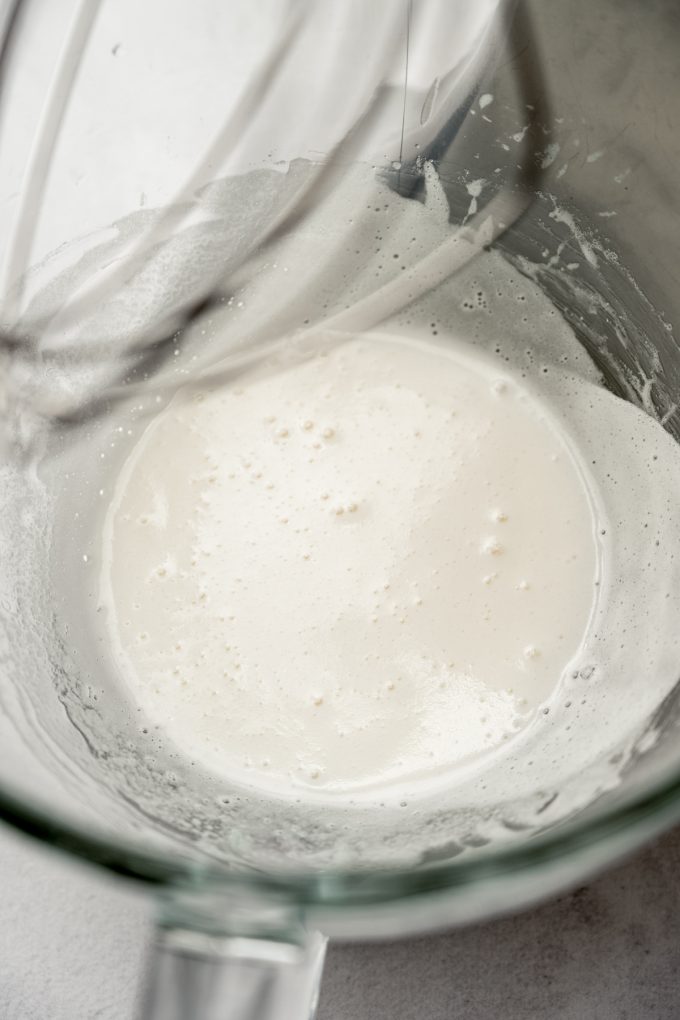 The bowl of a stand mixer with the beginnings of marshmallow meringue in it.
