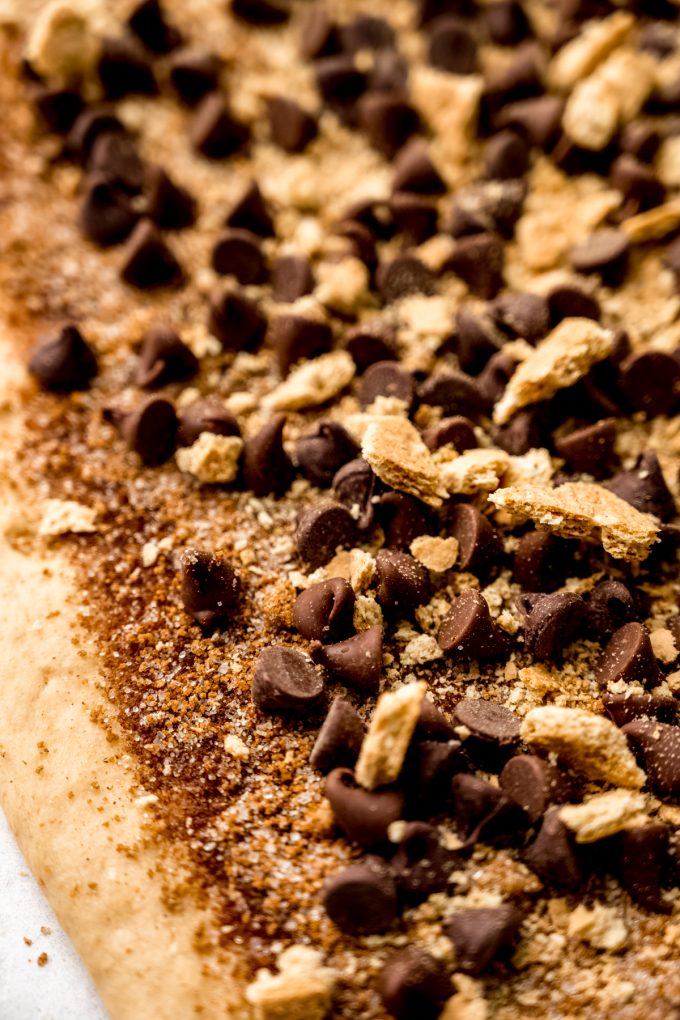 S'mores cinnamon roll dough in a rectangle with the filling on it before it gets rolled up.