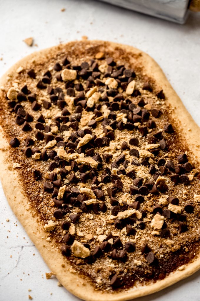 S'mores cinnamon roll dough in a rectangle with the filling on it before it gets rolled up.