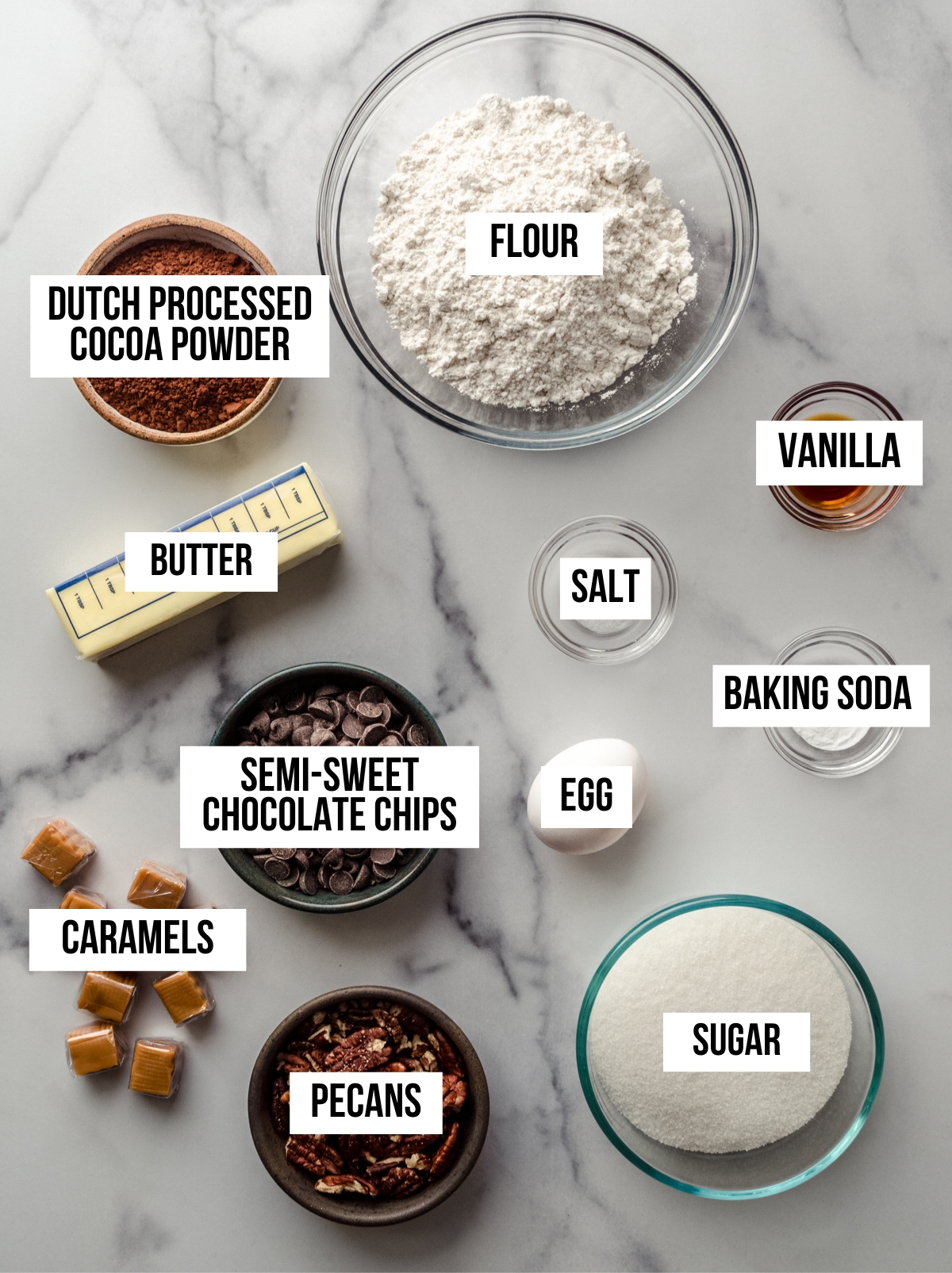 Aerial photo of ingredients to make chocolate turtle cookies with text overlay labeling each ingredient.