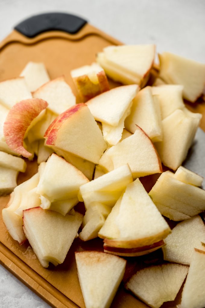 A pile of apple slices on a cutting board.