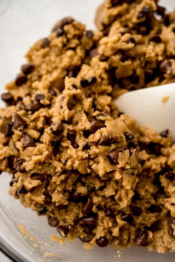 A bowl of fall spiced chocolate chip cookie dough with a spatula in it.