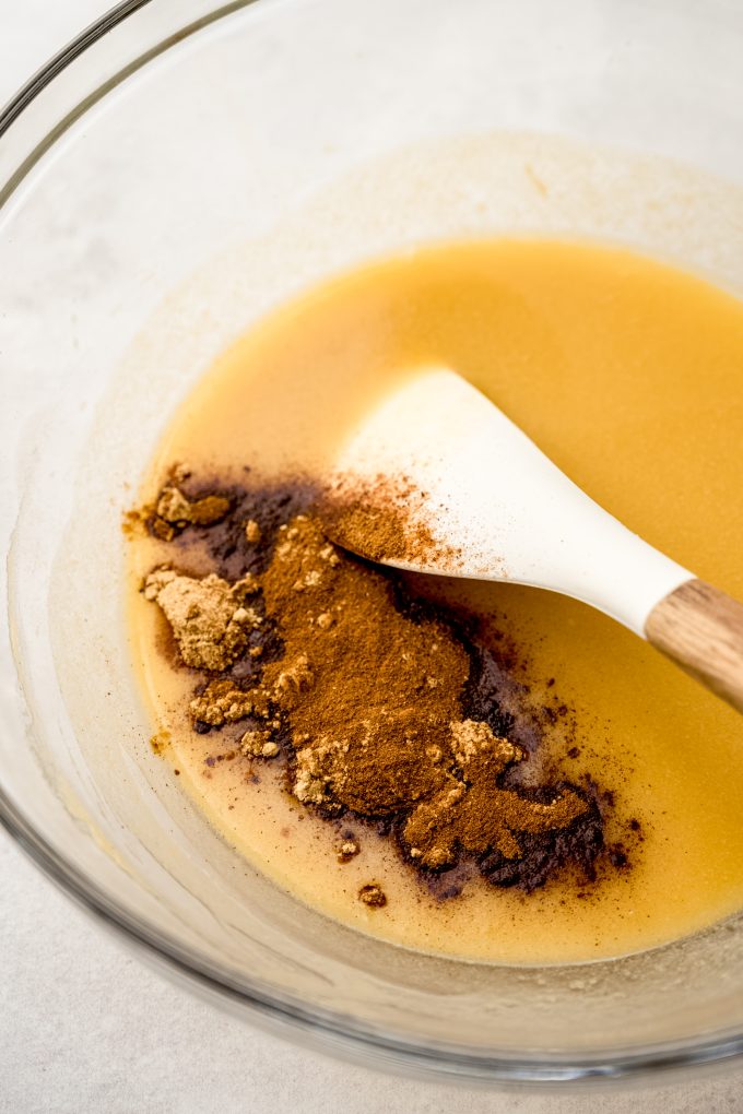 A bowl of melted butter that has spices and a spatula in it.