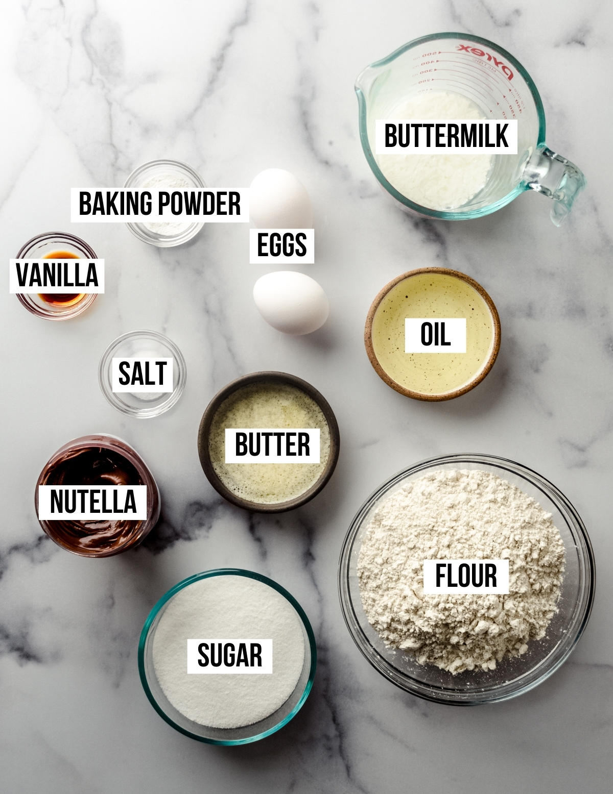 Aerial photo of ingredients to make Nutella muffins with text overlay labeling each ingredient.