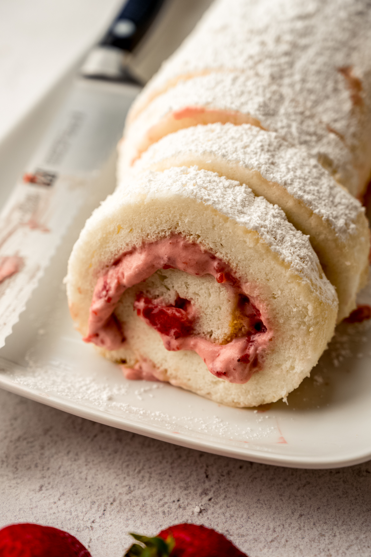 A strawberry Swiss roll cake on a plate.