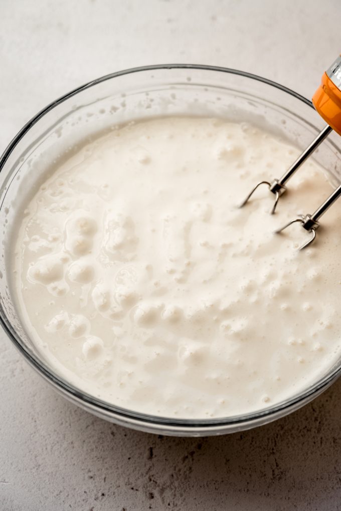 The batter for the sponge portion of a Swiss roll cake in a bowl with an electric mixer.