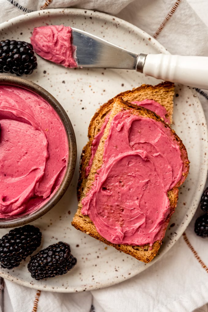 Aerial photo of blackberry butter in a bowl with a slice of toast that has some spread on it.