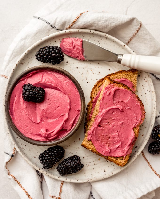 Aerial photo of blackberry butter in a bowl with a slice of toast that has some spread on it.