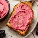 A photo of toast spread with homemade blackberry butter on a plate.