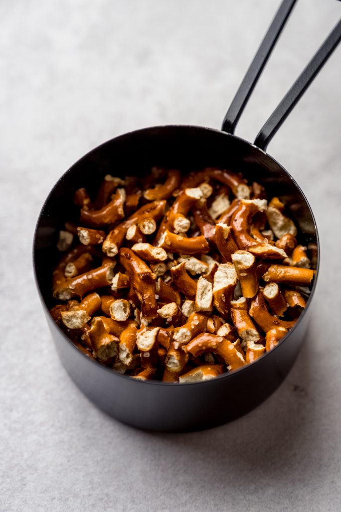 A measuring cup full of chopped pretzels.