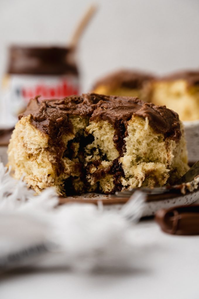 A Nutella roll on a plate with a bite taken out of it so you can see the inside.