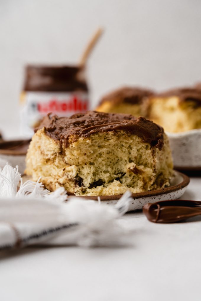 A Nutella roll on a plate with a jar of Nutella in the background.