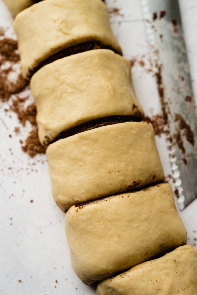 A log of Nutella cinnamon roll dough sliced into individual rolls.