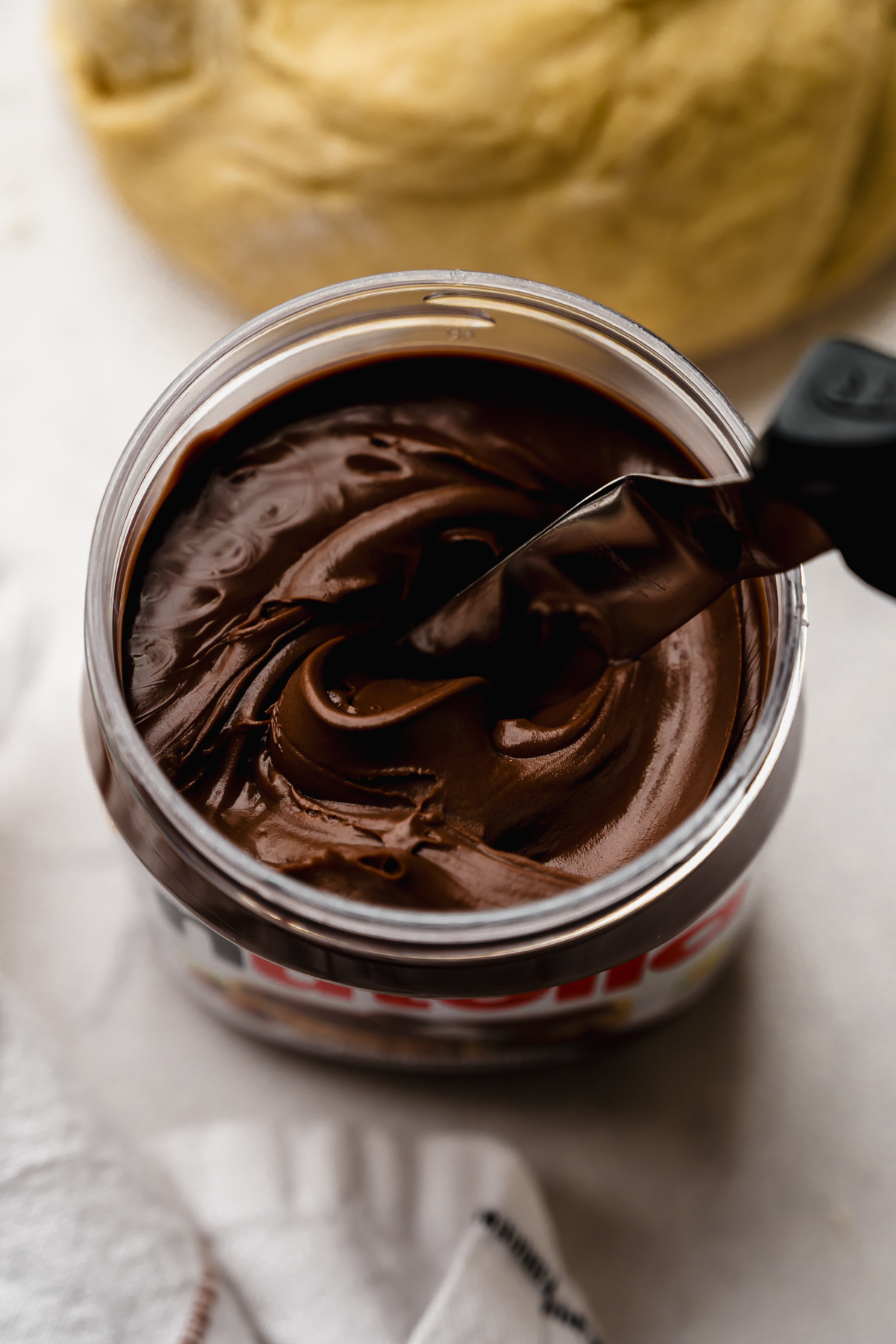 A jar of Nutella with an offset metal spatula in it.