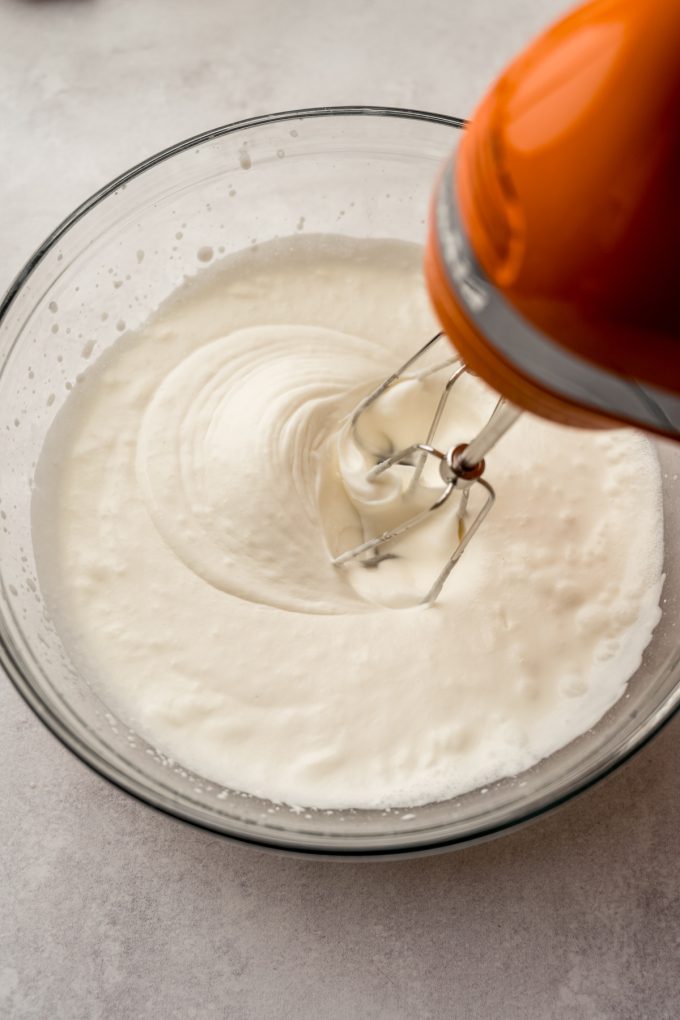 Someone is using an electric mixer to beat heavy cream to make whipped cream.