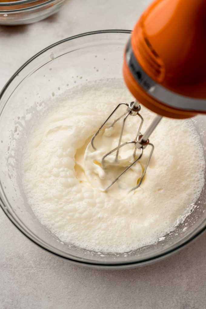 Someone is using an electric mixer to beat heavy cream to make whipped cream.