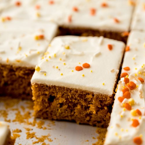 Sliced pumpkin sheet cake sitting in a baking pan.