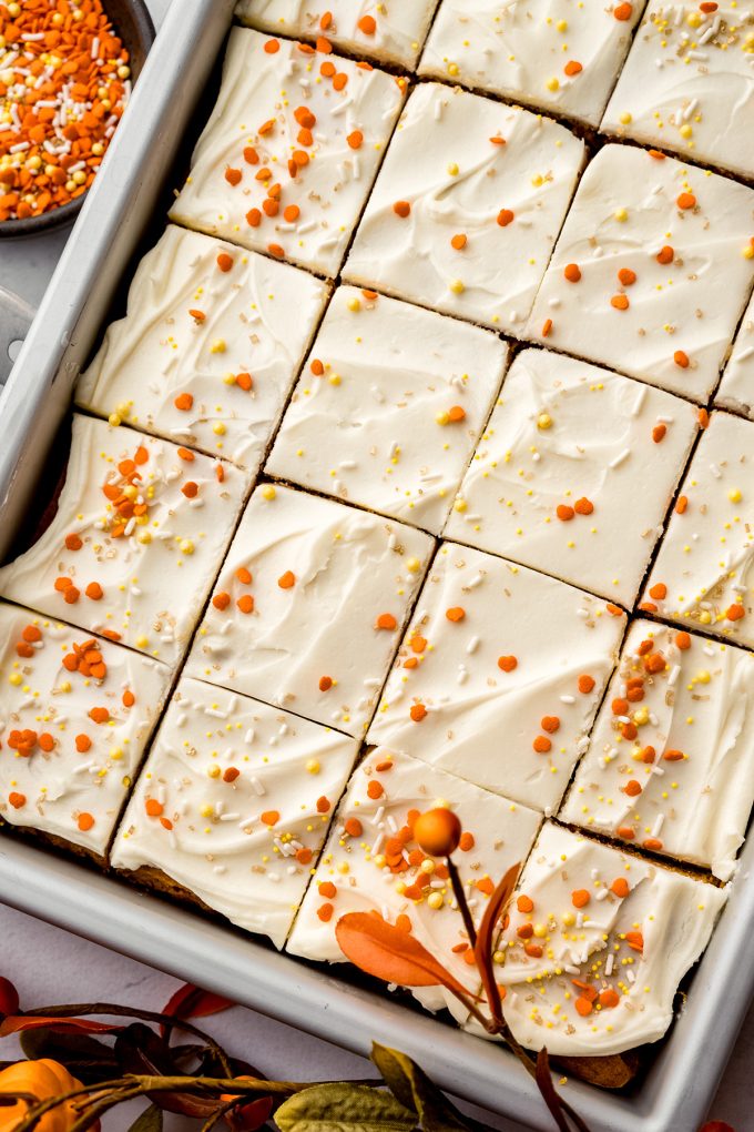 An aerial photo of sliced pumpkin sheet cake in a baking pan.
