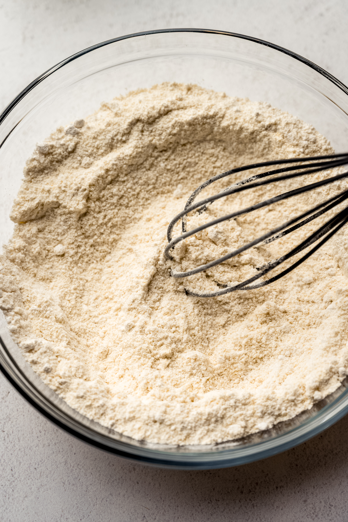 Someone is whisking together the dry ingredients for cornbread in a large bowl.