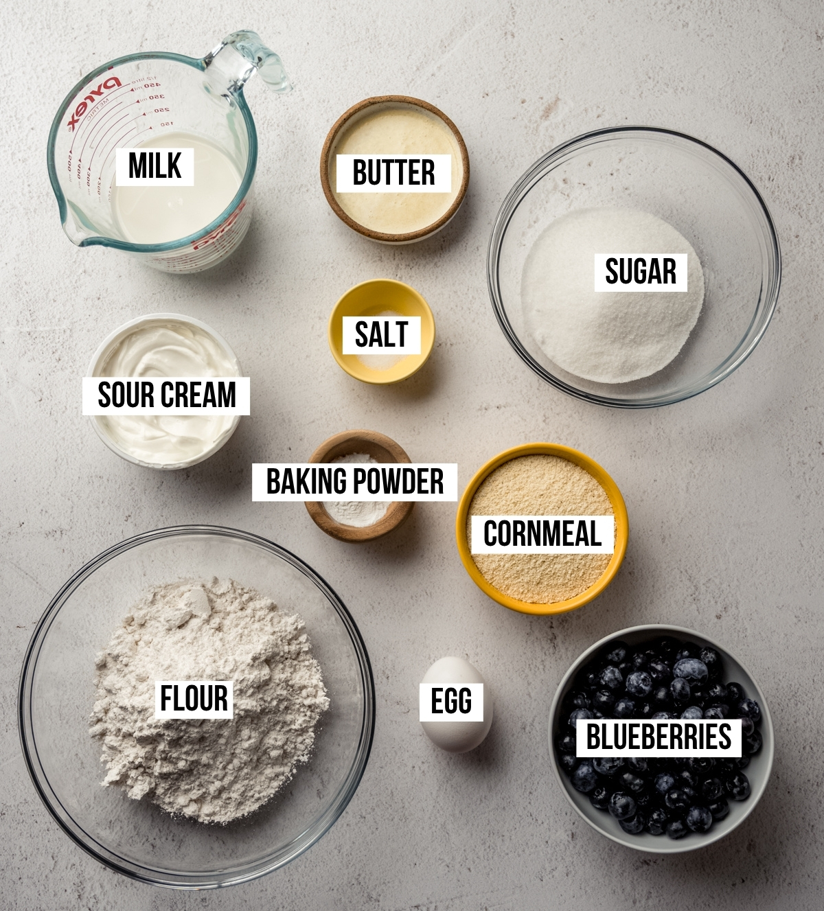 Aerial photo of ingredients to make blueberry cornbread with text overlay labeling each ingredient.