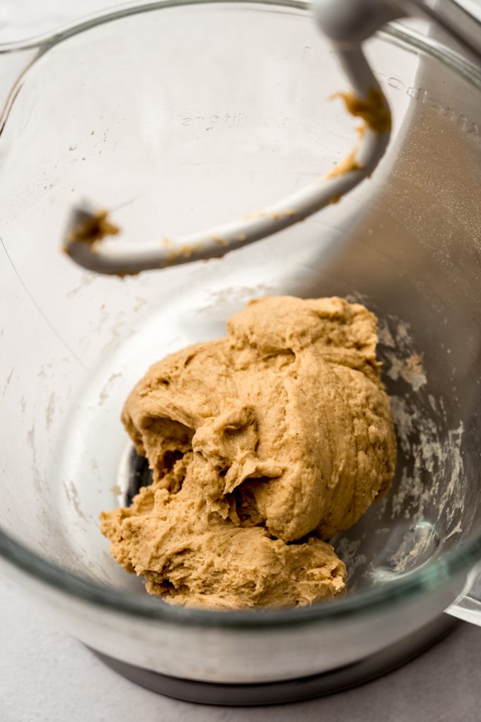 A bowl of a stand mixer with shaggy chai cinnamon roll dough in it.