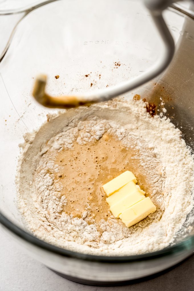 A bowl of a stand mixer with ingredients in it to make the dough for chai cinnamon rolls.