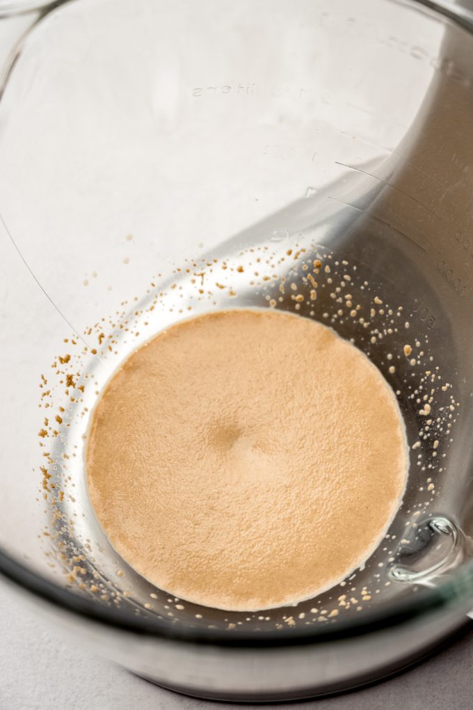 A bowl of a stand mixer with chai-infused milk and yeast in it.