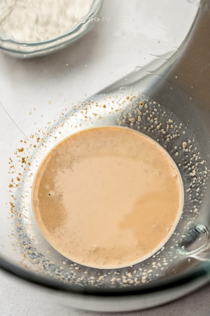 A bowl of a stand mixer with chai-infused milk and yeast in it.