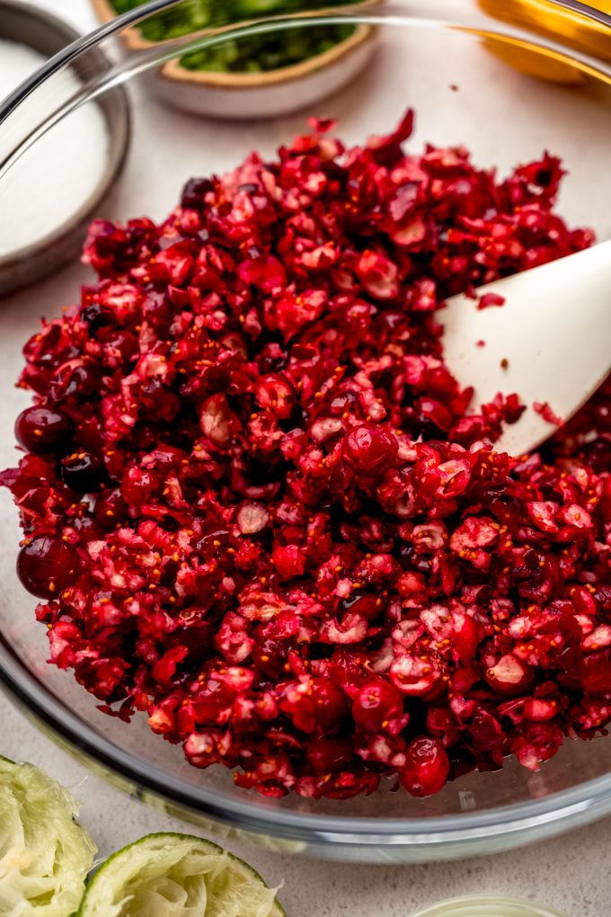 A bowl of chopped fresh cranberries with a spatula in it.
