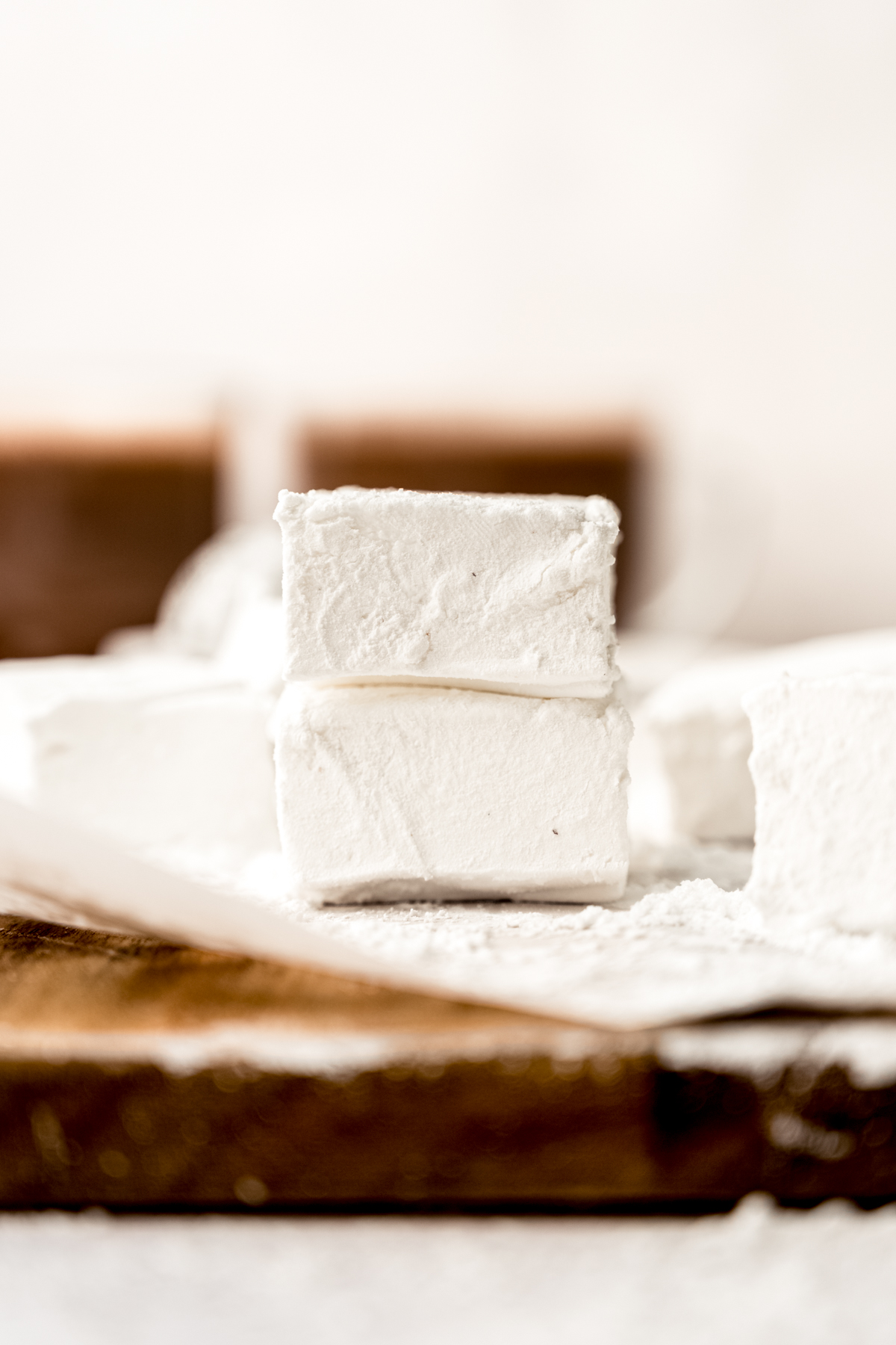 Two homemade marshmallows in a stack on a surface.