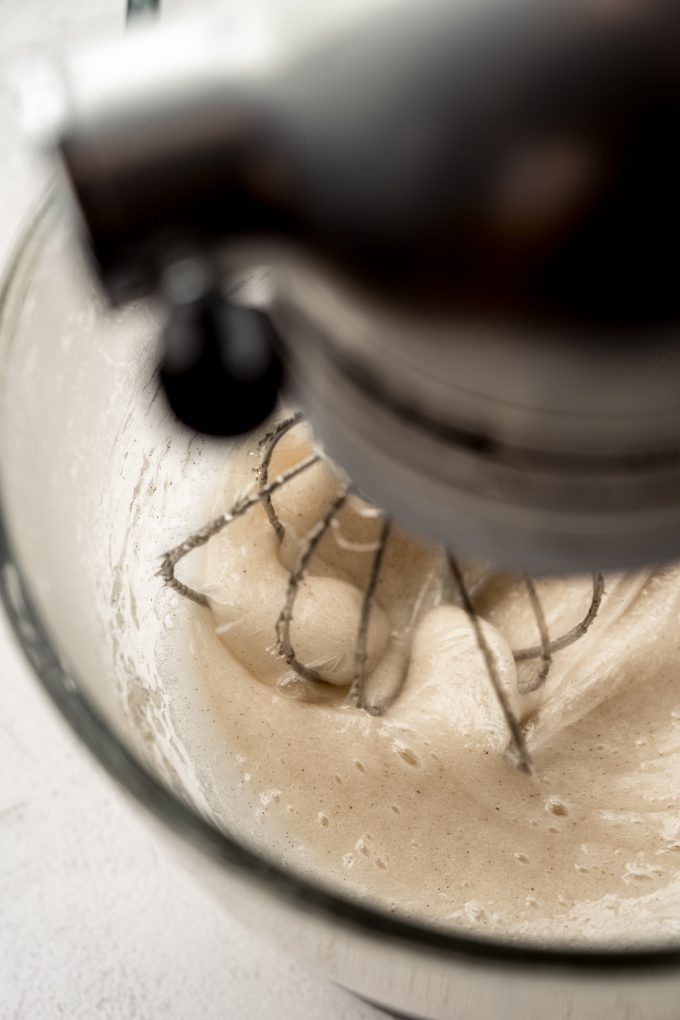 A mixer with homemade marshmallow mixture in the bowl with the whisk attachment.