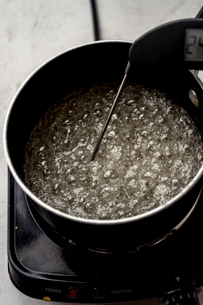 A saucepan of boiling sugar syrup with a digital thermometer in it.