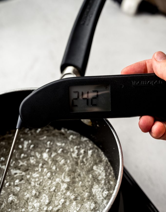 A saucepan of boiling sugar syrup with a digital thermometer in it.