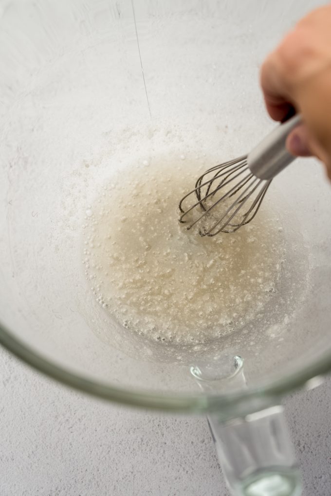 Someone is whisking together water and gelatin in the bottom of a bowl.