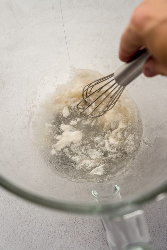 Someone is whisking together water and gelatin in the bottom of a bowl.