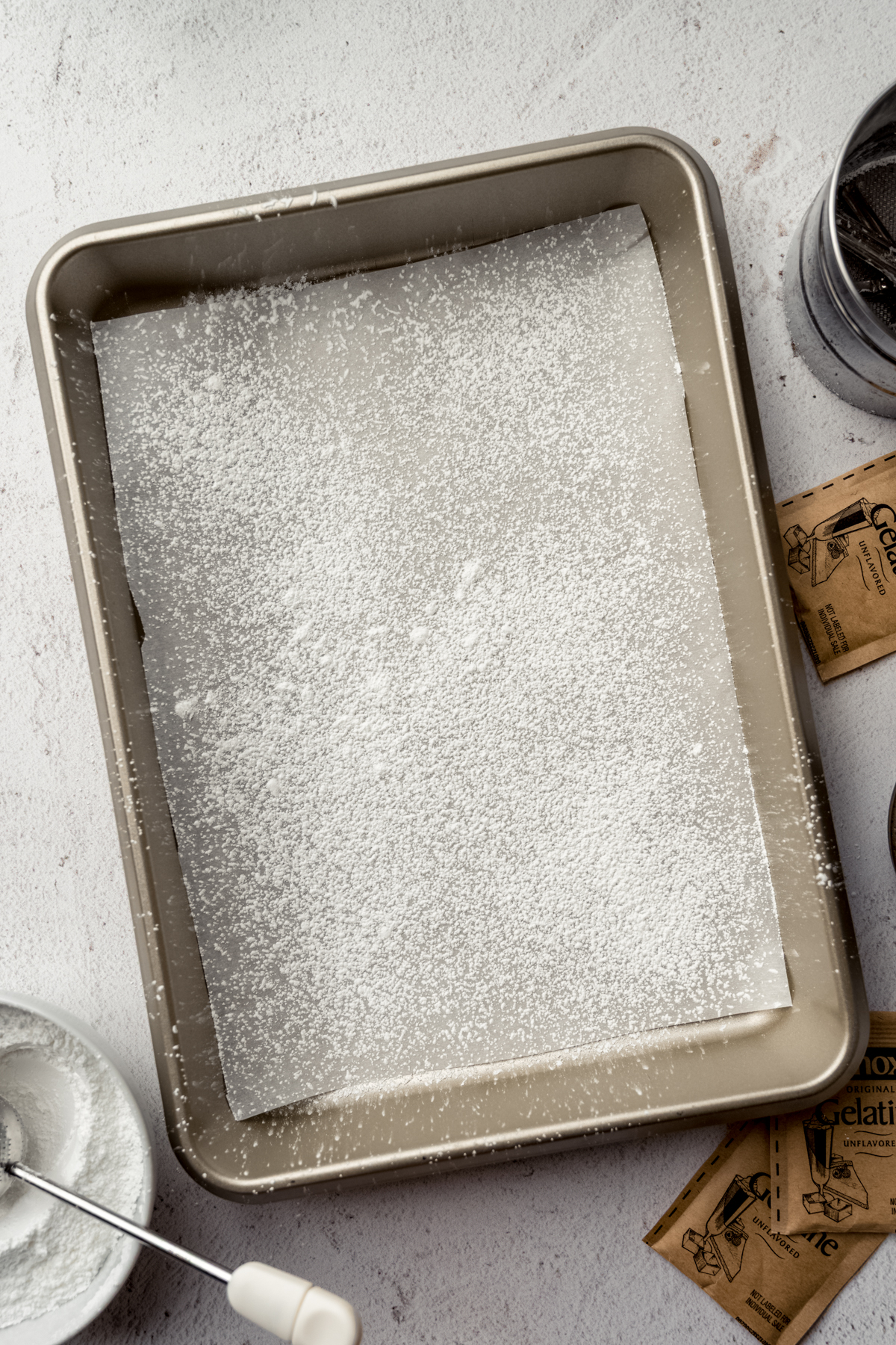 A baking pan lined with parchment and sprinkled with powdered sugar and cornstarch.