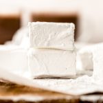 Two homemade marshmallows in a stack on a surface.