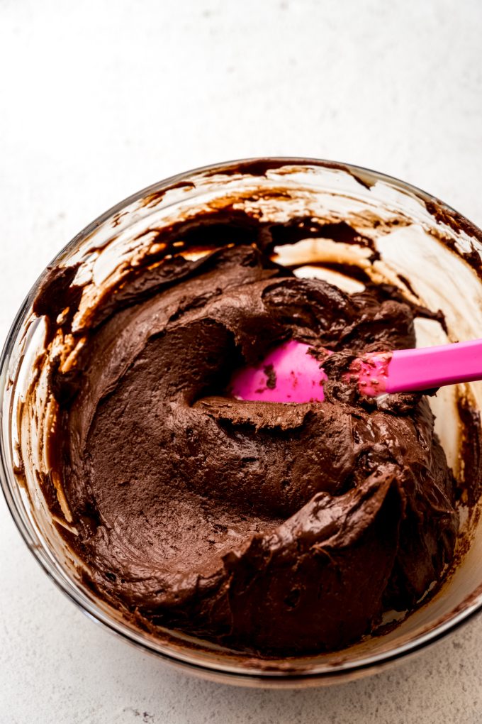 A mixture of chocolate chips, butter, and sweetened condensed milk in a bowl with a spatula to make microwave fudge.