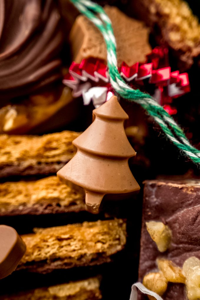 A Christmas tree shaped peanut butter meltaway in a container with other holiday candies.