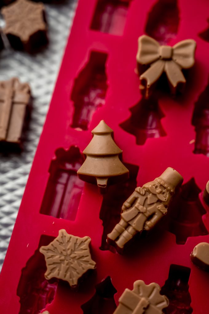 A candy mold on a baking sheet with peanut butter meltaways on and around it.