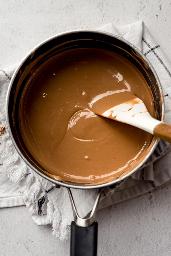 Someone is stirring a saucepan with peanut butter meltaway mixture in it.