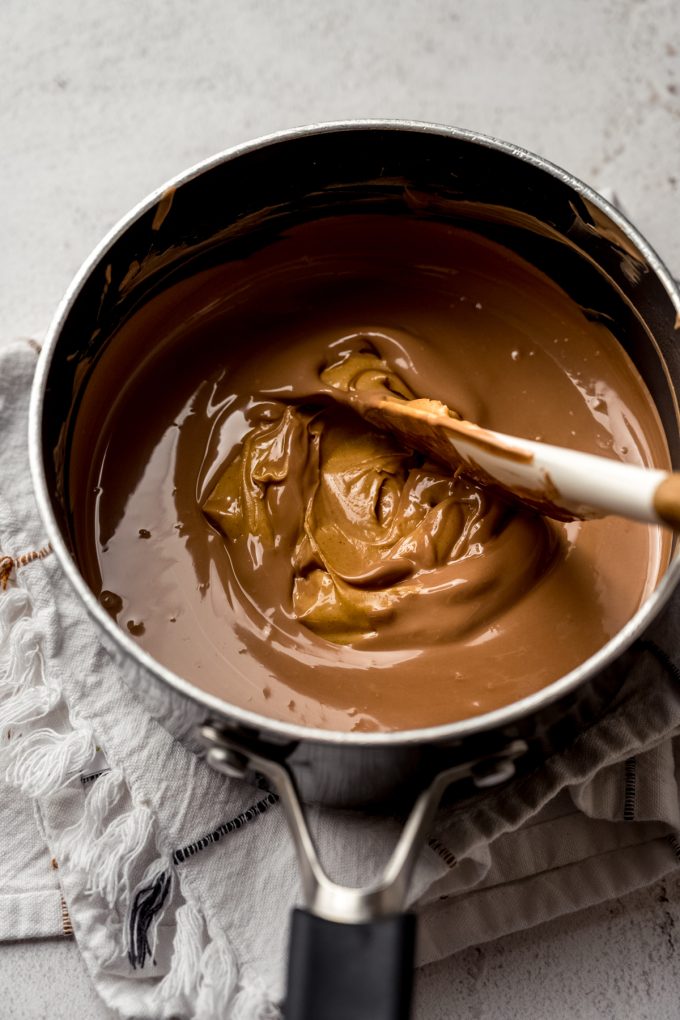 Someone is stirring a saucepan with peanut butter meltaway mixture in it.