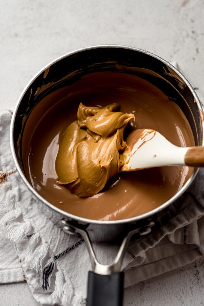 Someone is stirring a saucepan with peanut butter meltaway mixture in it.