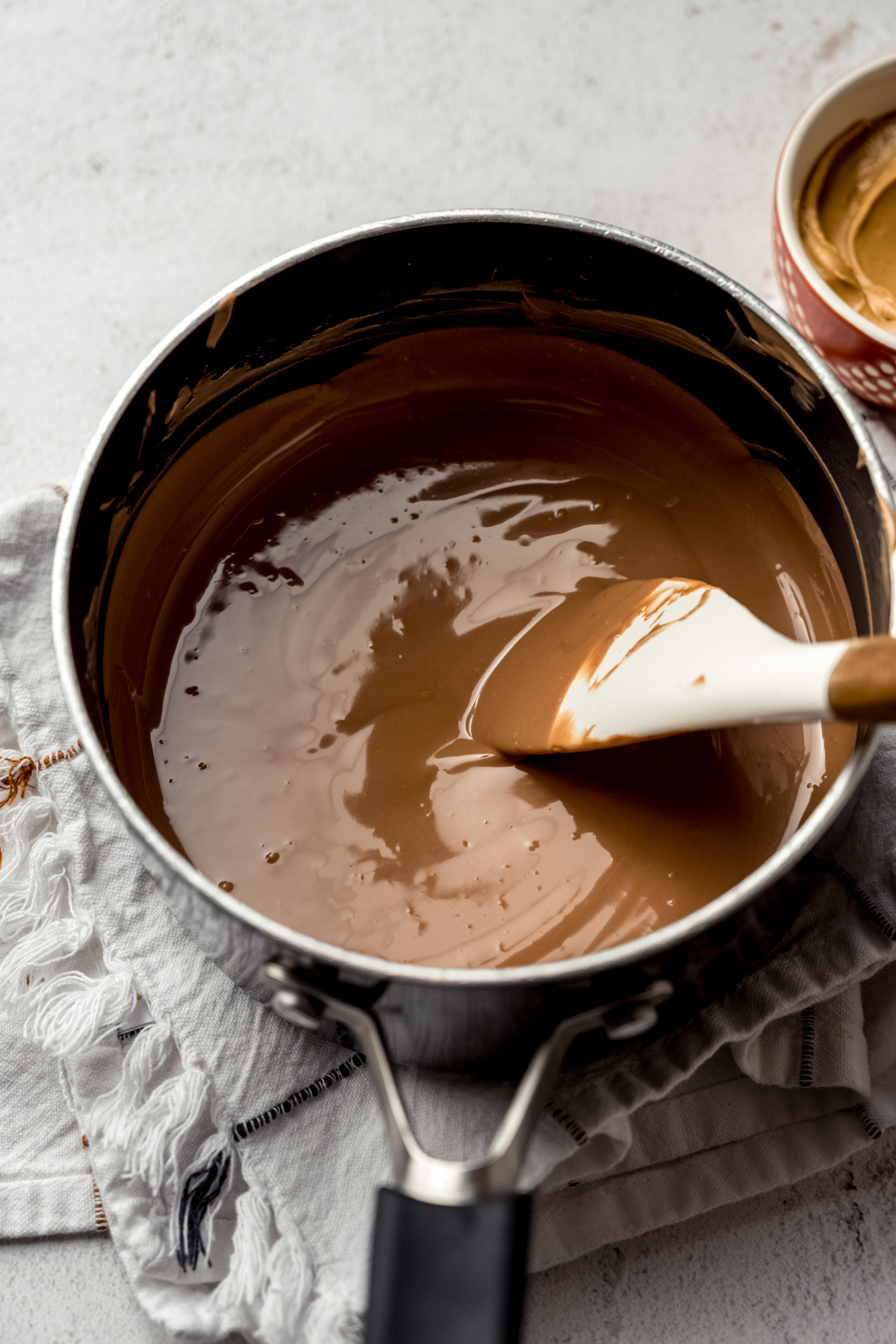 Someone is stirring a saucepan with peanut butter meltaway mixture in it.