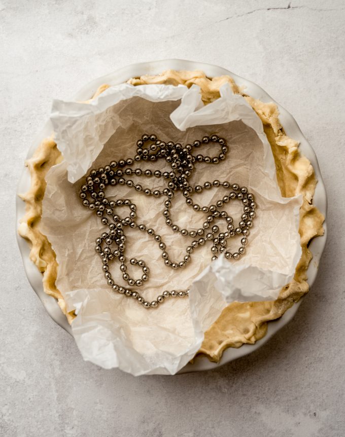 Aerial photo of a pie plate fitted with a pie dough that has parchment and pie weights in it.