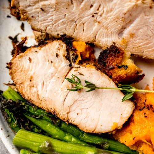 An aerial photo of a plate of turkey tenderloin, asparagus, and sweet potatoes.