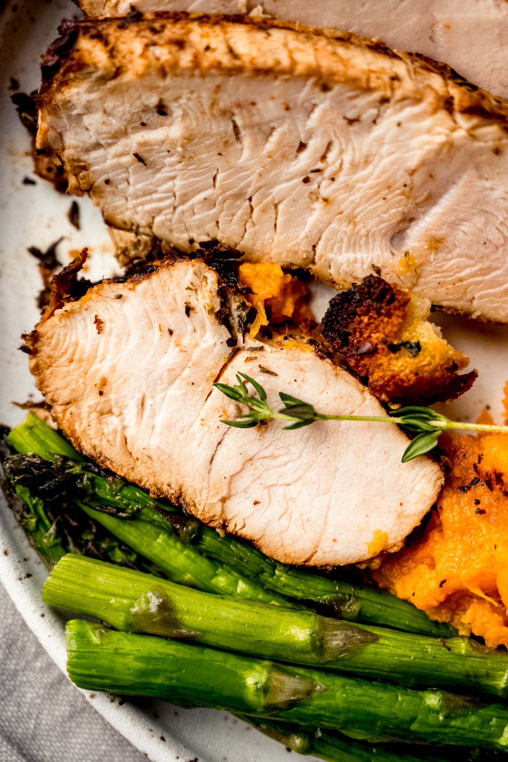 An aerial photo of a plate of turkey tenderloin, asparagus, and sweet potatoes.